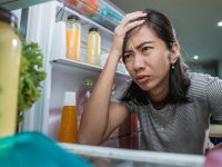 Unhappy Young Asian Woman Looking Inside The Fridge